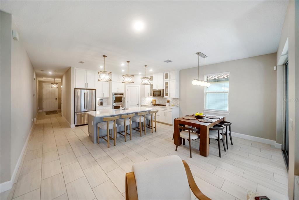 A living room with a sofa and two chairs opens into a kitchen with island seating — 3312 BIG SKY WAY, BRADENTON, FL