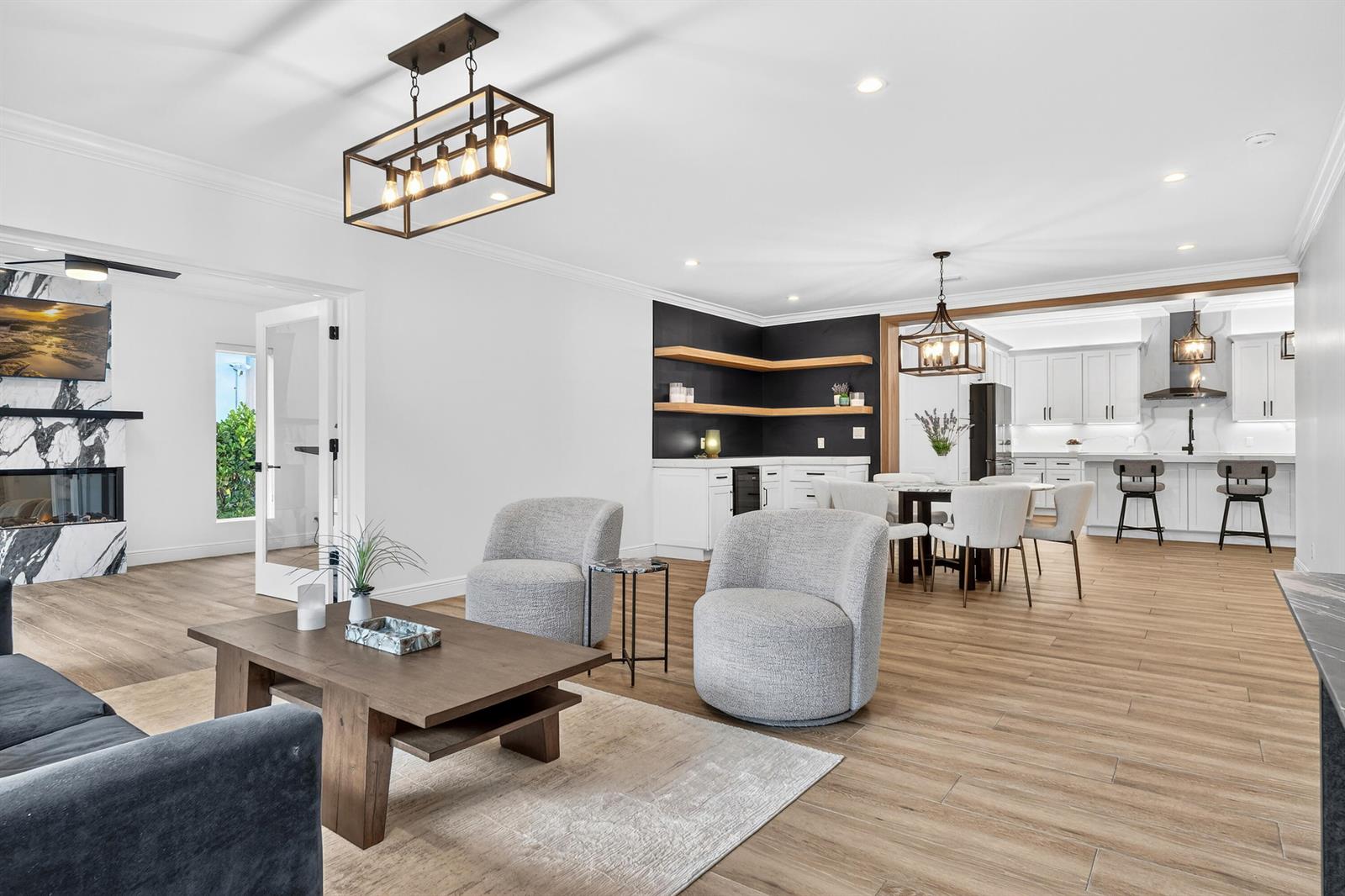An open-concept living area features a marble fireplace, a dining space, and a modern kitchen — 301 Pilgrim Road, West Palm Beach FL 33405, WEST PALM BEACH, FL