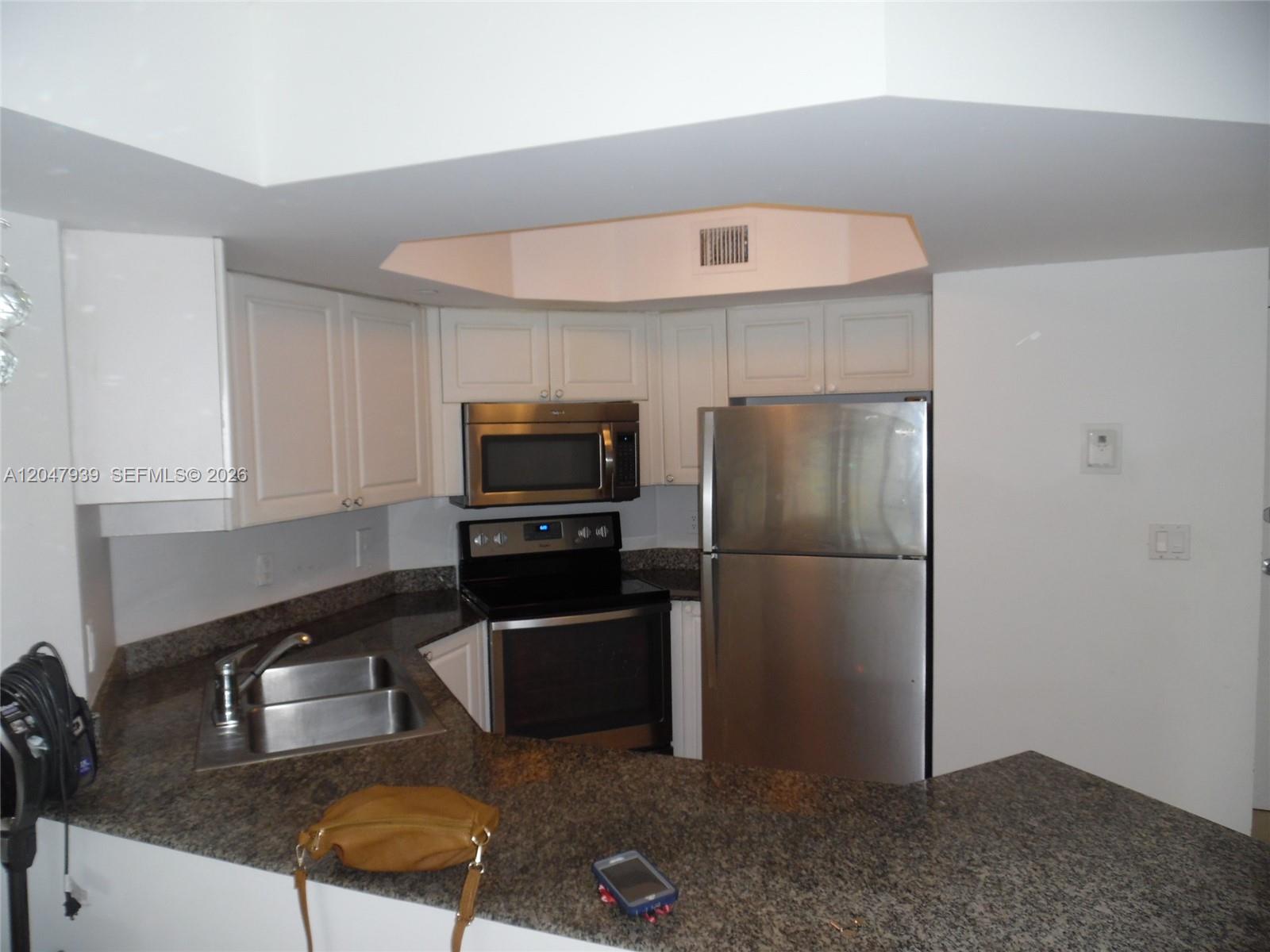A kitchen features white cabinets, stainless steel appliances, and granite countertops — 8911 Collins Ave # 1102, Surfside FL 33154, SURFSIDE, FL