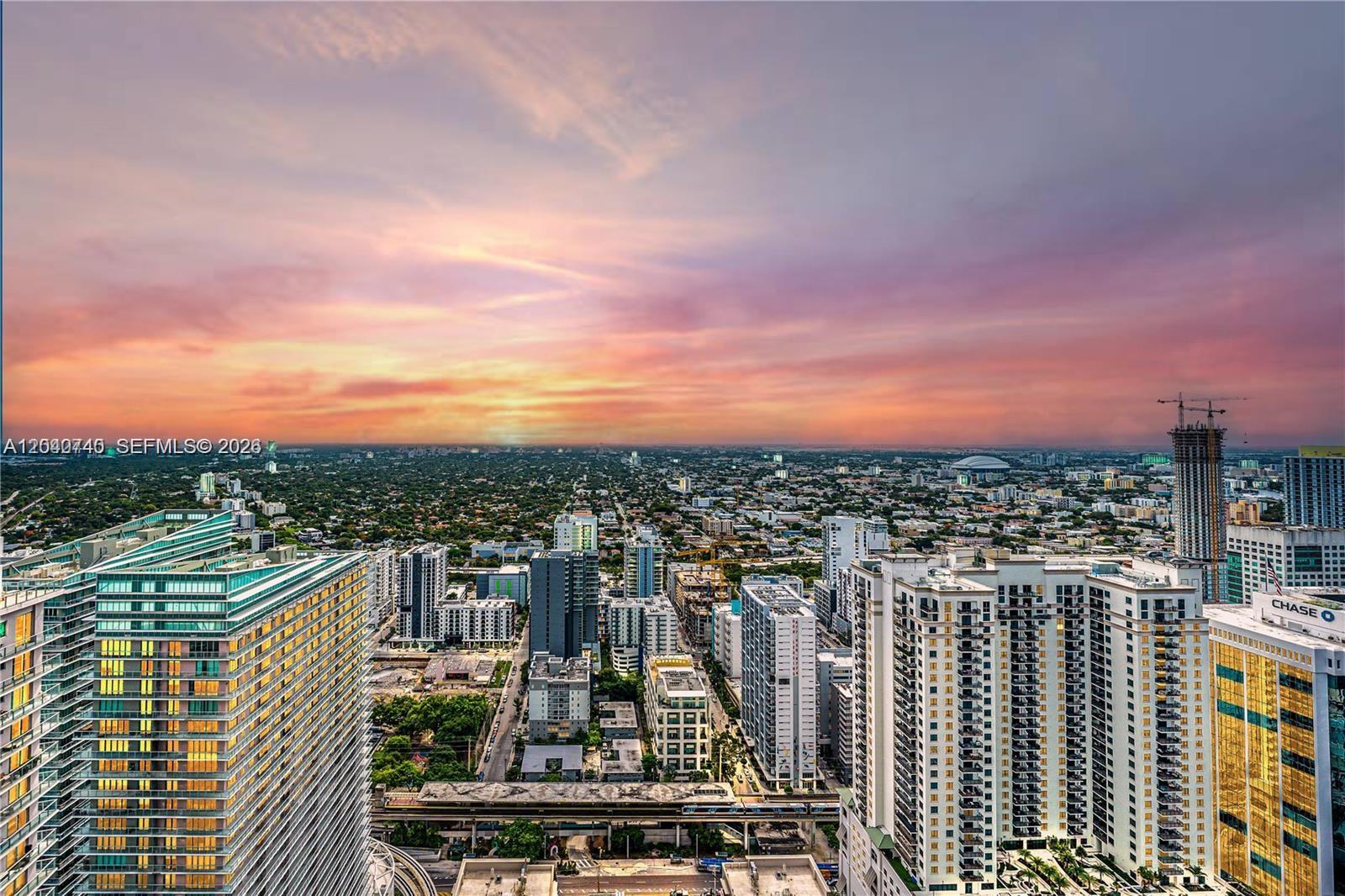 An elevated view of a city skyline at sunset with high-rise buildings and a train track — 1000 Brickell Plz # 4906, Miami FL 33131, MIAMI, FL