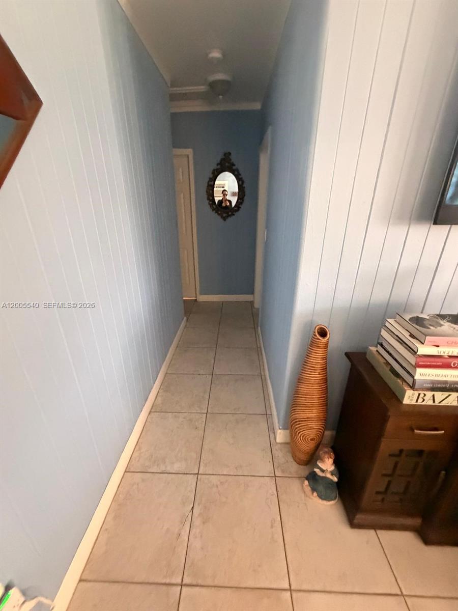 A hallway with light blue paneled walls, tile flooring, and a decorative mirror — 2835 SW 37th Ct # 1, Miami FL 33134, MIAMI, FL