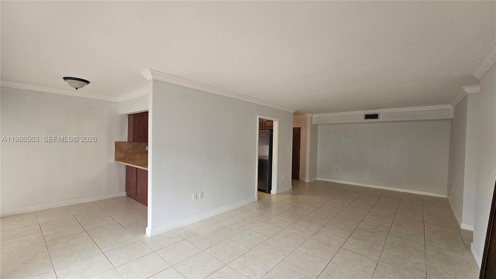 A kitchen features wood cabinets, stainless steel appliances, and tan countertops over tiled flooring — 5800 SW 127th Ave # 2109, Miami FL 33183, MIAMI, FL