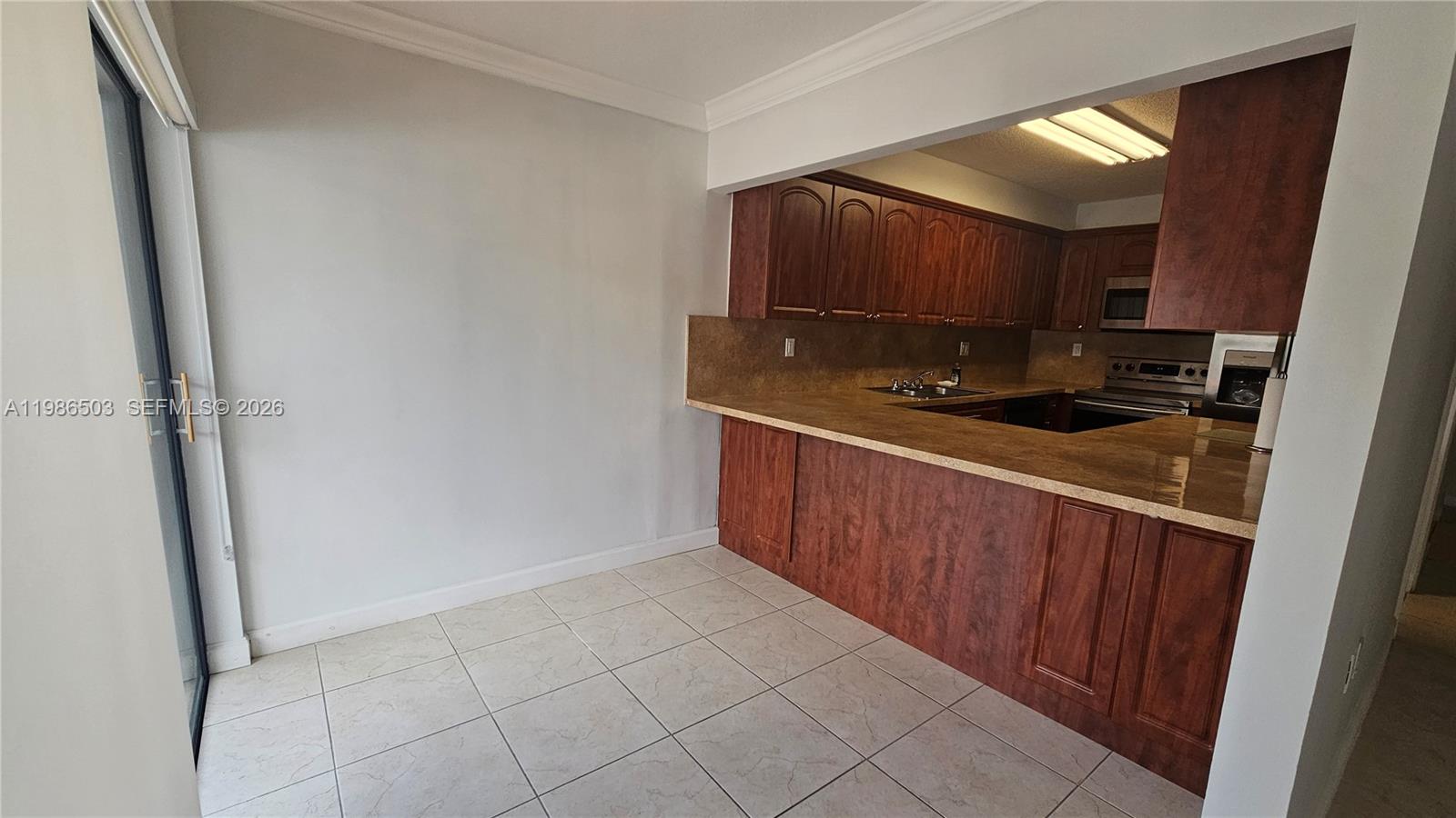 A laundry area features a washer and dryer tucked under a countertop with wooden cabinets — 5800 SW 127th Ave # 2109, Miami FL 33183, MIAMI, FL