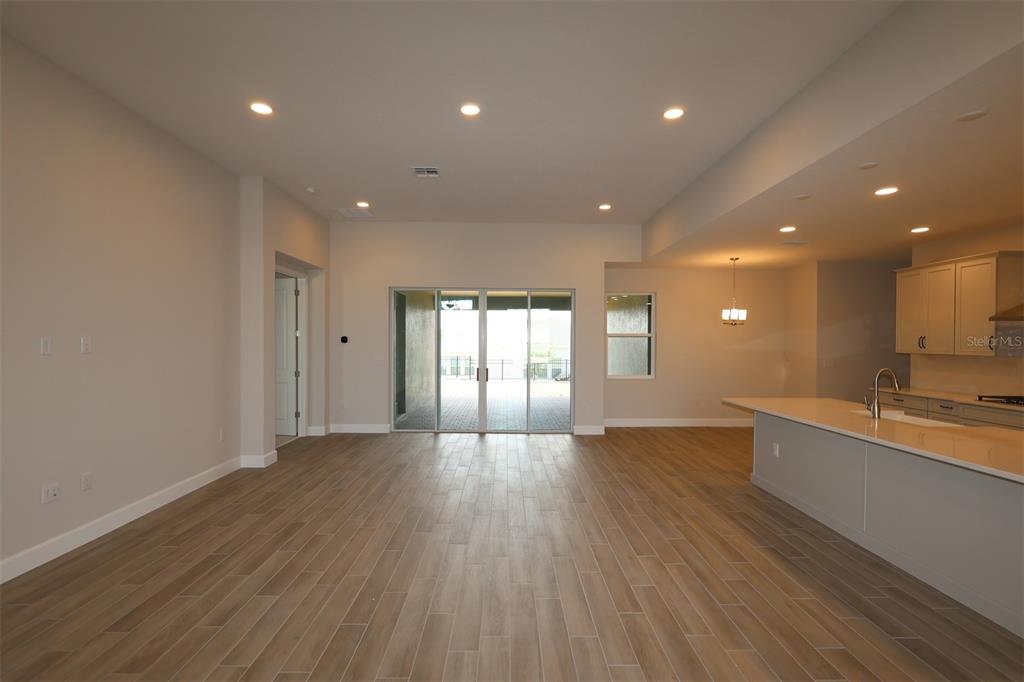 An open-concept kitchen and living area features light wood-look tile flooring and recessed lighting — 3177 WOLF LAKE AVENUE, APOPKA, FL