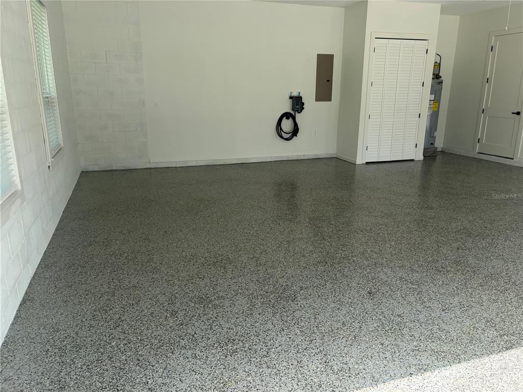 A garage with a speckled epoxy floor, white block walls, and a water heater closet — 1148 TURNER LANE, ALTAMONTE SPRINGS, FL