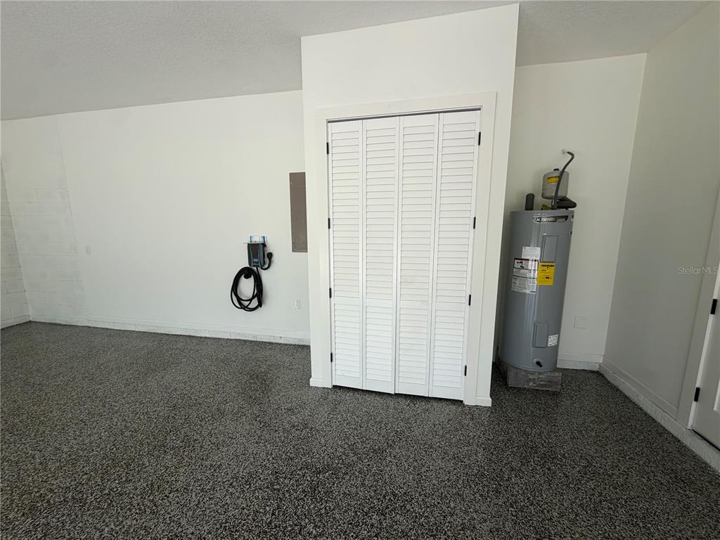 A garage interior features a speckled epoxy floor, a water heater, and a storage closet — 1148 TURNER LANE, ALTAMONTE SPRINGS, FL