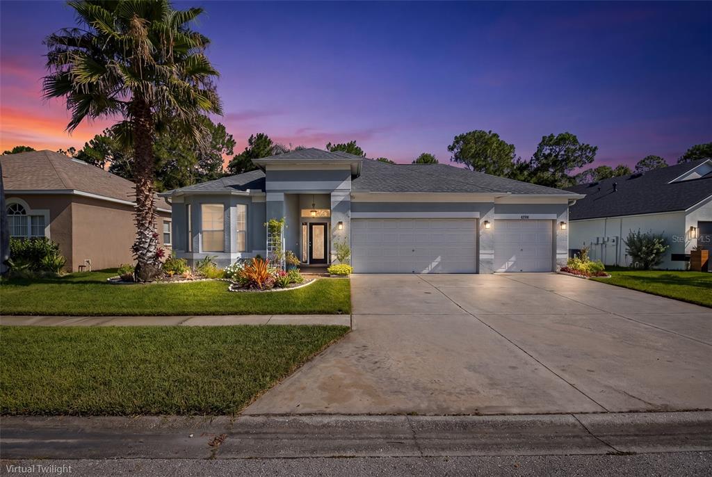 A single-story house with a two-car garage, palm tree, and landscaped yard at twilight — 12709 WESTWOOD LAKES BOULEVARD, TAMPA, FL