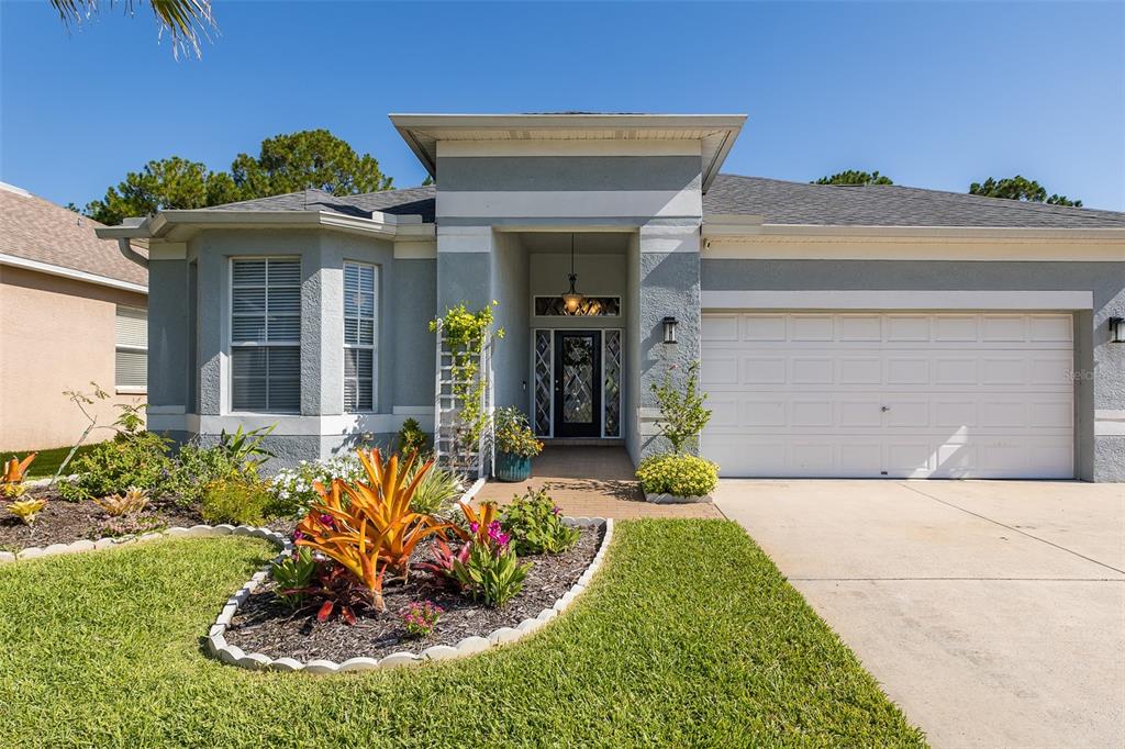 A single-story house with a gray stucco exterior, a two-car garage, and a landscaped yard — 12709 WESTWOOD LAKES BOULEVARD, TAMPA, FL