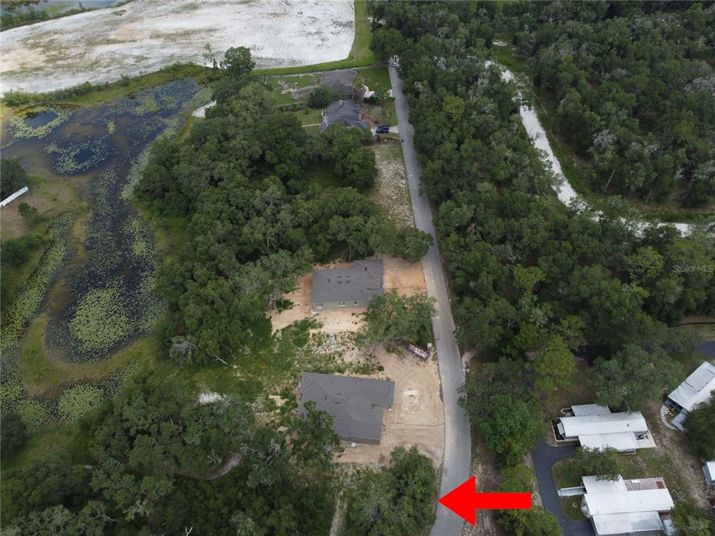 An aerial view shows houses situated along a road next to a pond and woods — 5078 WESTLAKE BOULEVARD, DADE CITY, FL