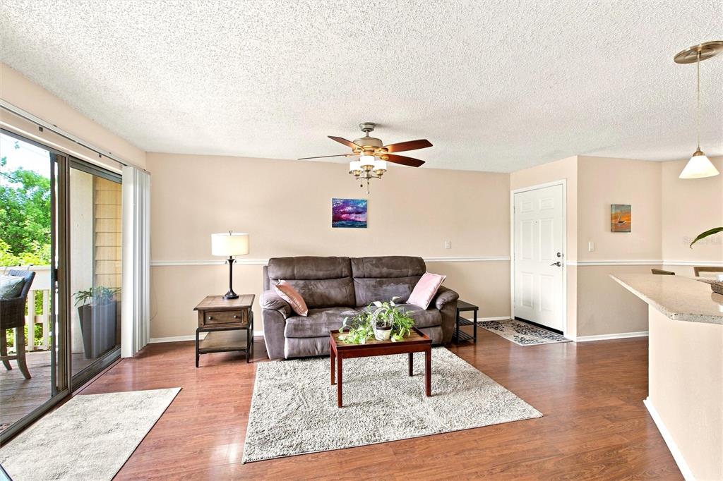 A living room features a brown sofa, a coffee table, and a ceiling fan — 115 112TH AVENUE NE UNIT 307, ST PETERSBURG, FL