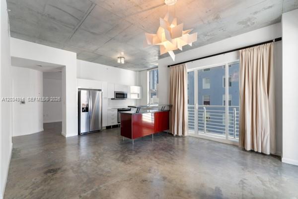 An open-concept kitchen and living area features concrete floors, a red island, and large windows — 133 NE 2nd Ave # 801, Miami FL 33132, MIAMI, FL