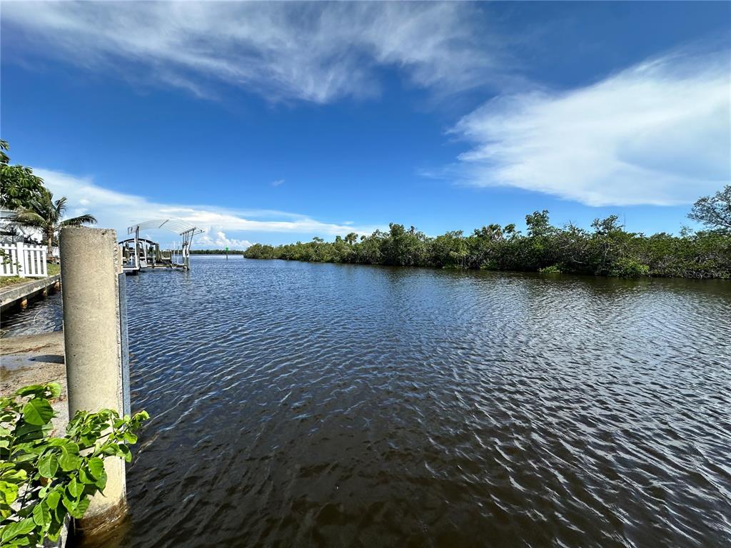 A view of a canal with a boat dock and dense mangroves under a blue sky — 17063 OHARA DRIVE, PORT CHARLOTTE, FL