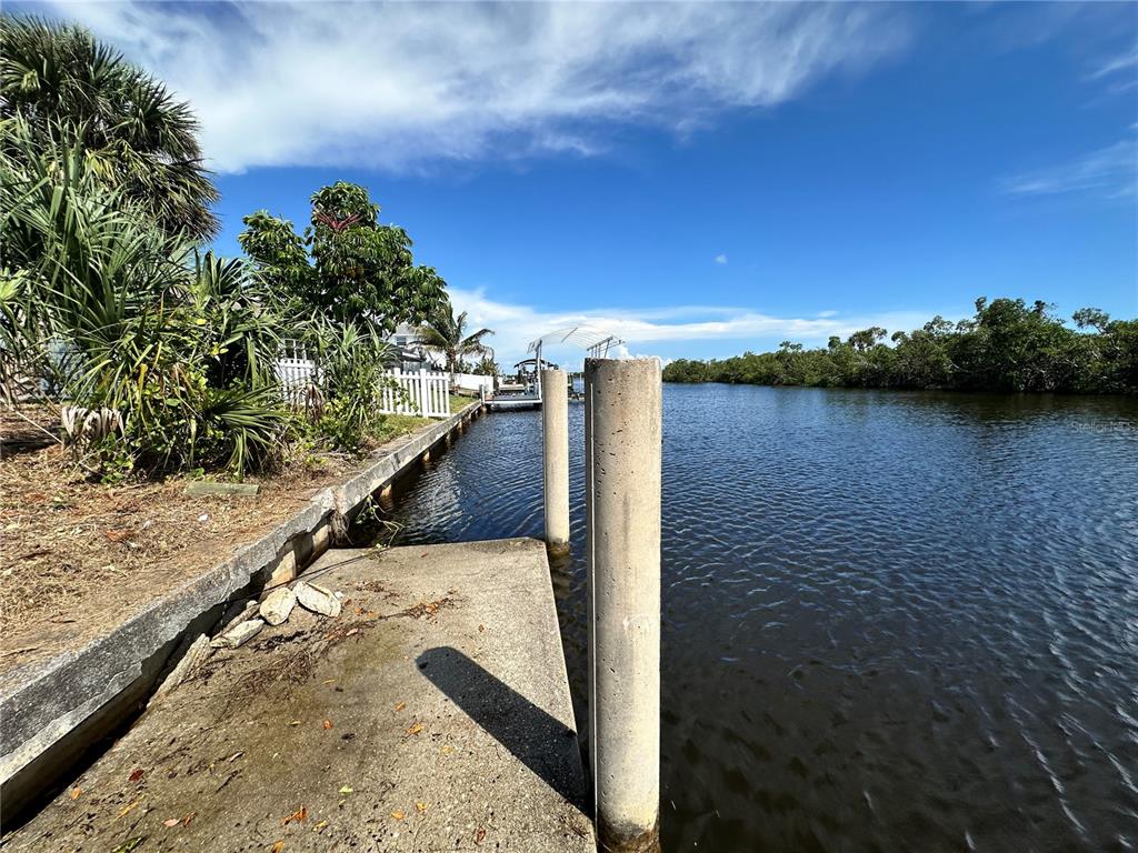 A concrete boat dock extends into a canal lined with mangroves and vegetation — 17063 OHARA DRIVE, PORT CHARLOTTE, FL