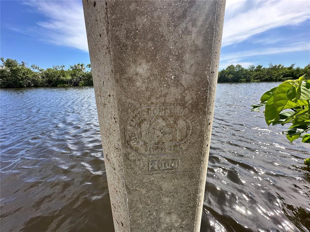 A close-up view of a concrete piling with an embossed stamp dated 2000 near water — 17063 OHARA DRIVE, PORT CHARLOTTE, FL