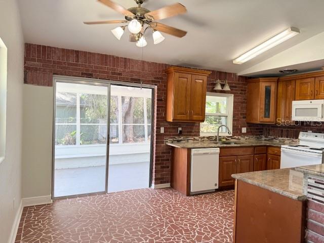 A kitchen features wood cabinets, a brick accent wall, and a tiled floor — 1092 EASTBROOK BOULEVARD, WINTER PARK, FL