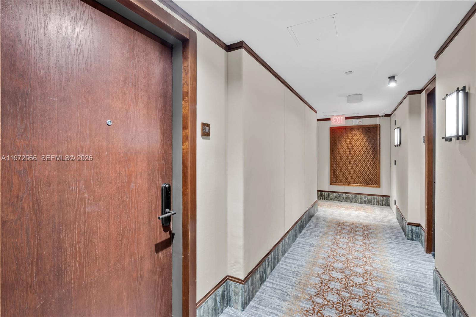 A wooden door with a digital lock opens into a carpeted residential building hallway — 101 20th St # 3806, Miami Beach FL 33139, MIAMI BEACH, FL