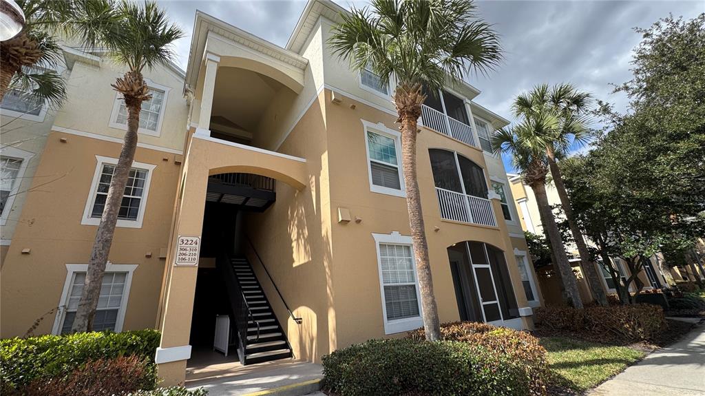 A three-story apartment building with tan stucco walls, screened balconies, and exterior staircases — 3224 DANTE DRIVE UNIT 207, ORLANDO, FL