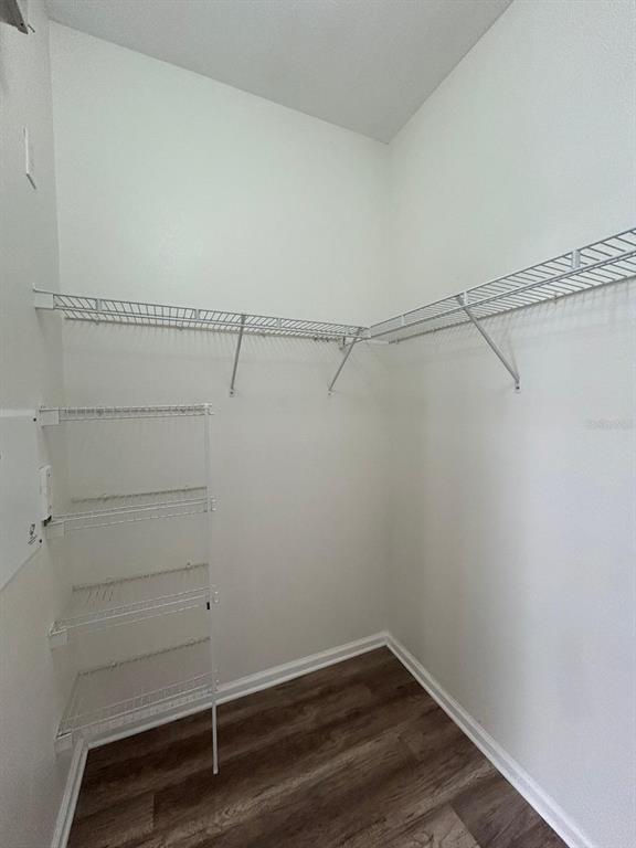 A walk-in closet features white wire shelving, light walls, and wood-look vinyl flooring — 3224 DANTE DRIVE UNIT 207, ORLANDO, FL