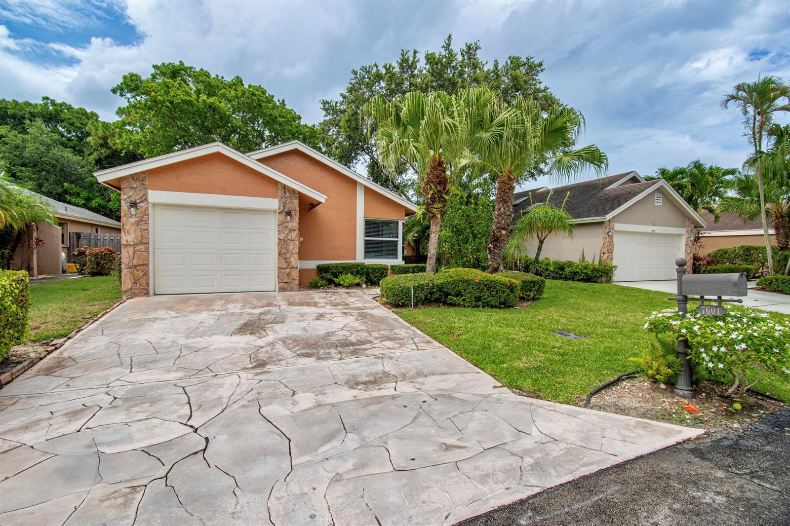 A single-story house with a cracked concrete driveway, stone accents, and palm trees — 7601 Martinique Boulevard, Boca Raton FL 33433, BOCA RATON, FL