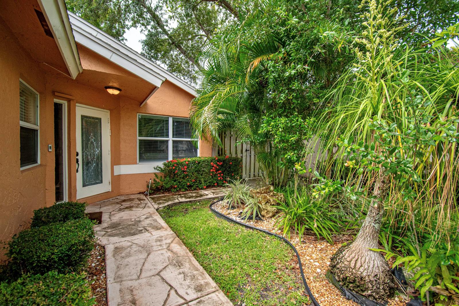 A stone walkway leads to the front entrance of a house with orange stucco walls — 7601 Martinique Boulevard, Boca Raton FL 33433, BOCA RATON, FL