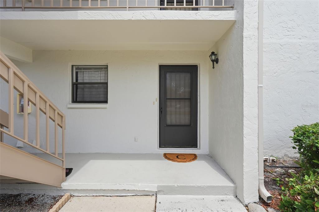 The exterior view shows a ground-level apartment entrance with a dark door and stairs — 1200 TARPON WOODS BOULEVARD UNIT N2, PALM HARBOR, FL