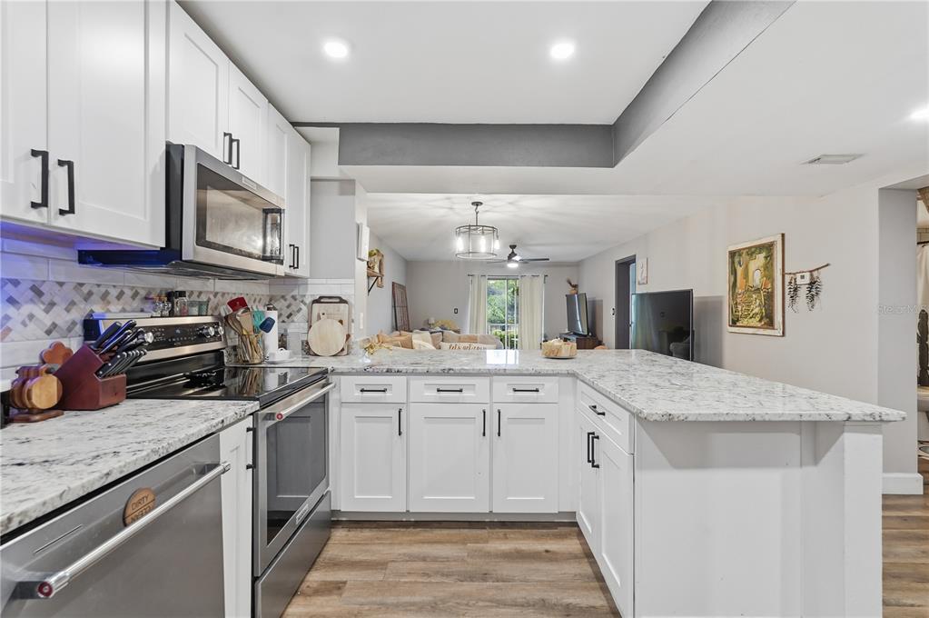 A kitchen with white cabinets, granite countertops, and stainless steel appliances opens to a living area — 1200 TARPON WOODS BOULEVARD UNIT N2, PALM HARBOR, FL