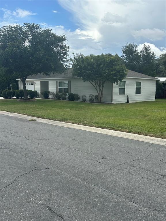 A single-story house with white siding and a garage sits on a grassy corner lot — 716 TRUMAN AVENUE, LADY LAKE, FL