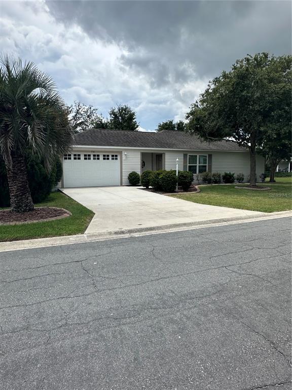 A single-story house with light siding, a white garage door, and a concrete driveway — 716 TRUMAN AVENUE, LADY LAKE, FL