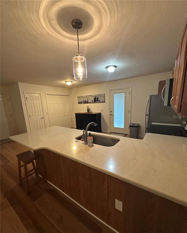 A kitchen features a white countertop island with a sink, wooden cabinets, and pendant lighting — 716 TRUMAN AVENUE, LADY LAKE, FL
