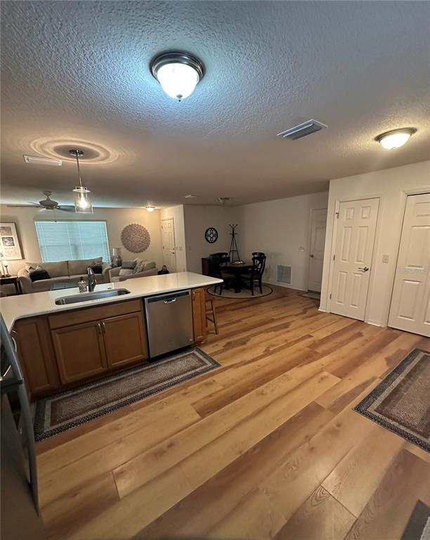 An open-concept kitchen and living area features light wood flooring, wooden cabinets, and white countertops — 716 TRUMAN AVENUE, LADY LAKE, FL