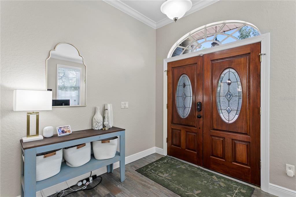 A foyer features a blue console table, a wall mirror, and double wooden entry doors — 3319 W VILLA ROSA STREET, TAMPA, FL
