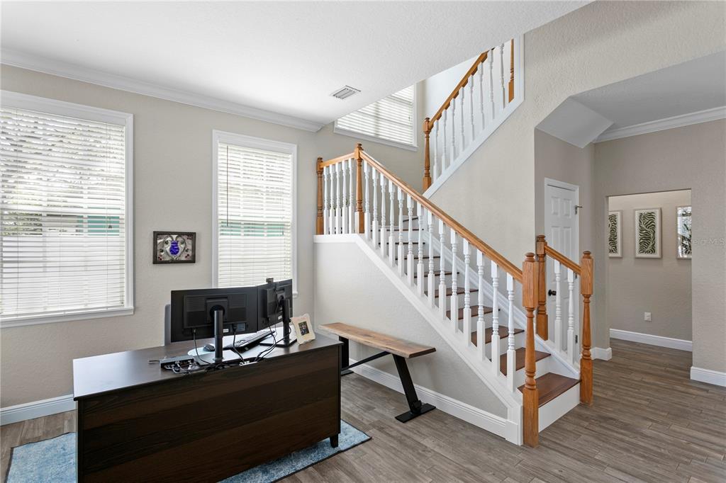 A home office features a dark wood desk, a staircase with white railings, and wood-look flooring — 3319 W VILLA ROSA STREET, TAMPA, FL