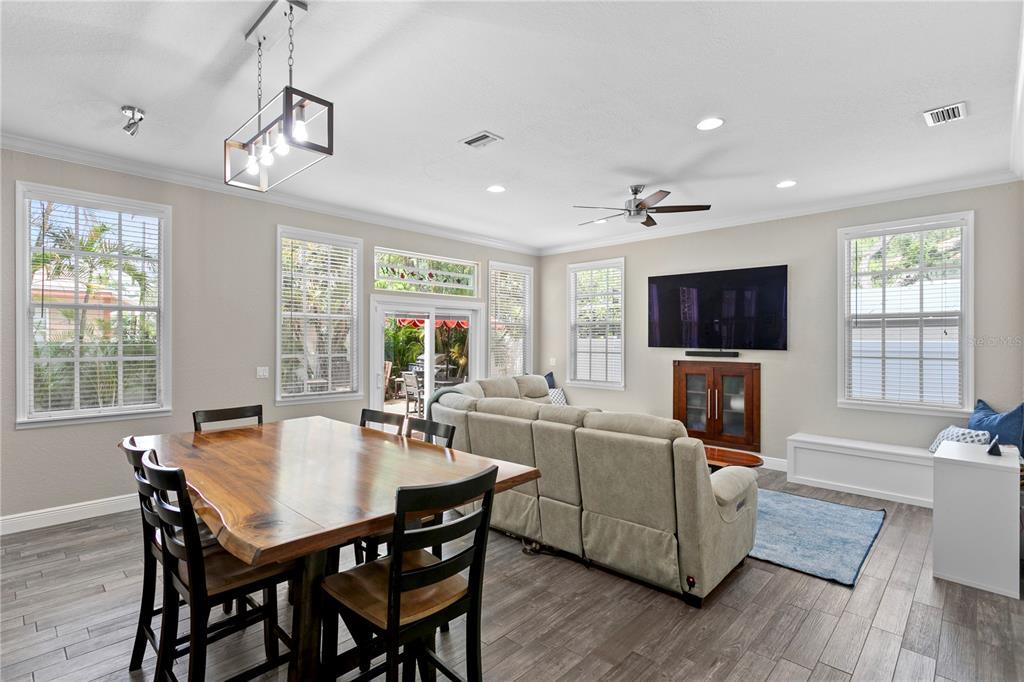A living room and dining area with wood-look tile floors, a sectional, and a television — 3319 W VILLA ROSA STREET, TAMPA, FL