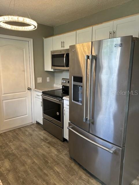 A kitchen features stainless steel appliances, white cabinetry, and wood-look flooring — 1135 SIBONEY STREET NW, PALM BAY, FL