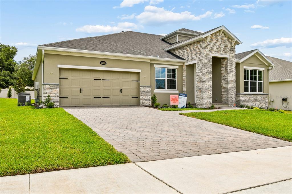 A single-story house with a stone facade, tan stucco, and a paved driveway — 3326 WOLF LAKE AVENUE, APOPKA, FL