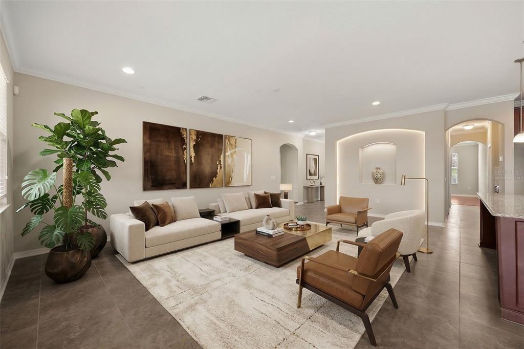 A living room with a beige sofa, leather armchairs, a coffee table, and a wall niche — 1831 VIA LAGO DRIVE, LAKELAND, FL