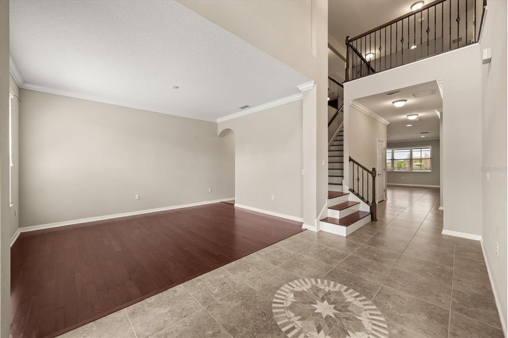 An interior view showing a living room with wood flooring, a tiled entryway, and stairs — 1831 VIA LAGO DRIVE, LAKELAND, FL