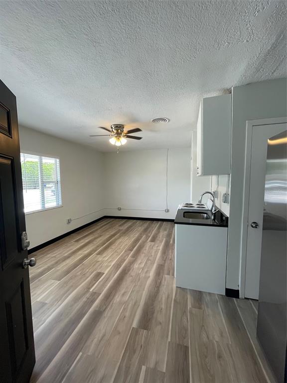 A studio apartment features light wood-look flooring, a ceiling fan, and a compact kitchenette — 707 ROSERY ROAD NW UNIT 3, LARGO, FL