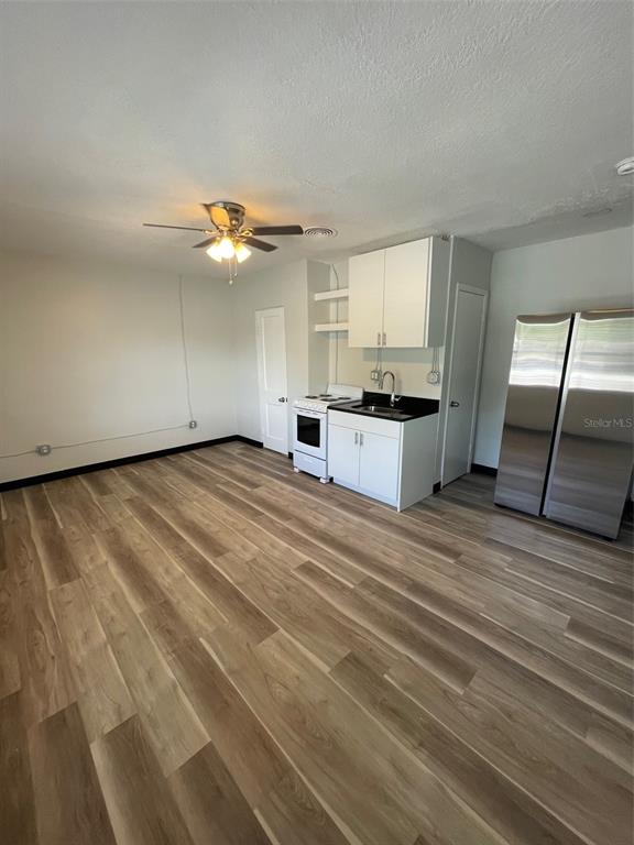 A small kitchen area with white cabinets, stainless steel appliances, and wood-look flooring — 707 ROSERY ROAD NW UNIT 3, LARGO, FL