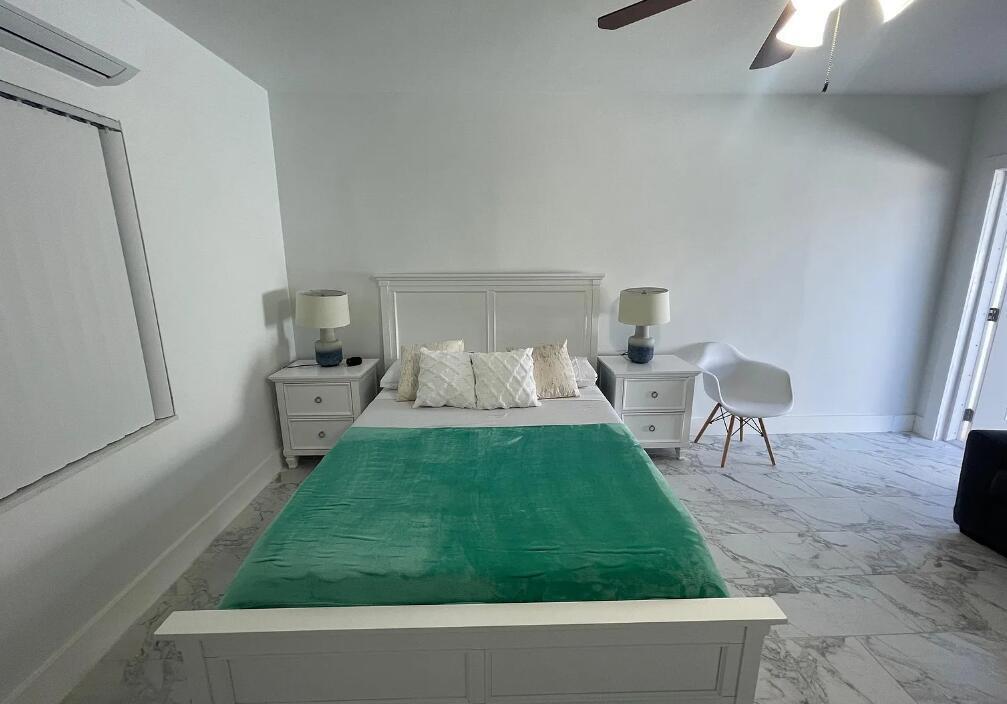 A bedroom features a white bed with a green blanket, two nightstands, and marble flooring — 201 S Ocean Boulevard # 7, Boca Raton FL 33432, BOCA RATON, FL