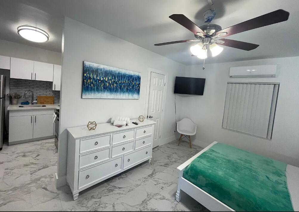A bedroom with a white dresser, a bed with a green blanket, and an attached kitchenette — 201 S Ocean Boulevard # 7, Boca Raton FL 33432, BOCA RATON, FL