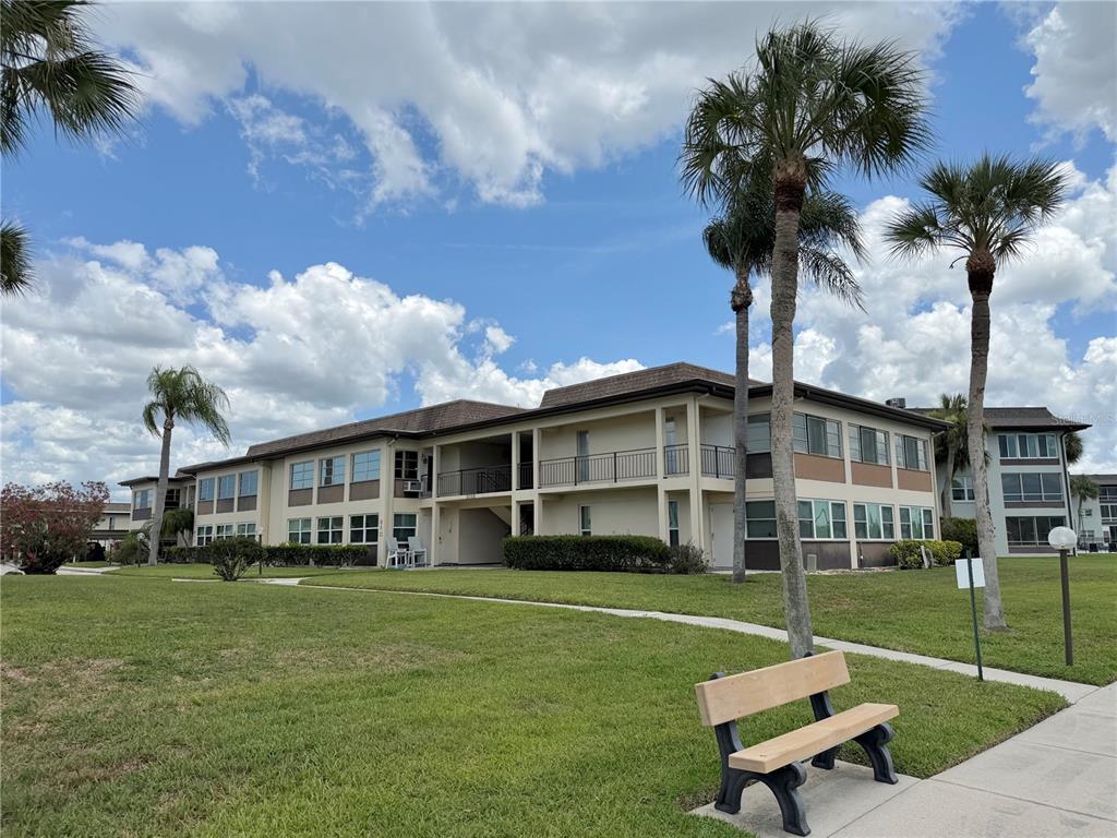 A view from a balcony overlooking a canal with boats, palm trees, and nearby houses — 5108 AMULET DRIVE UNIT 205, NEW PORT RICHEY, FL