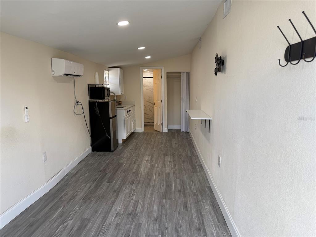 A studio apartment features a kitchenette, a bathroom entrance, and light wood-look flooring — 5620 1ST STREET UNIT rear, ZEPHYRHILLS, FL