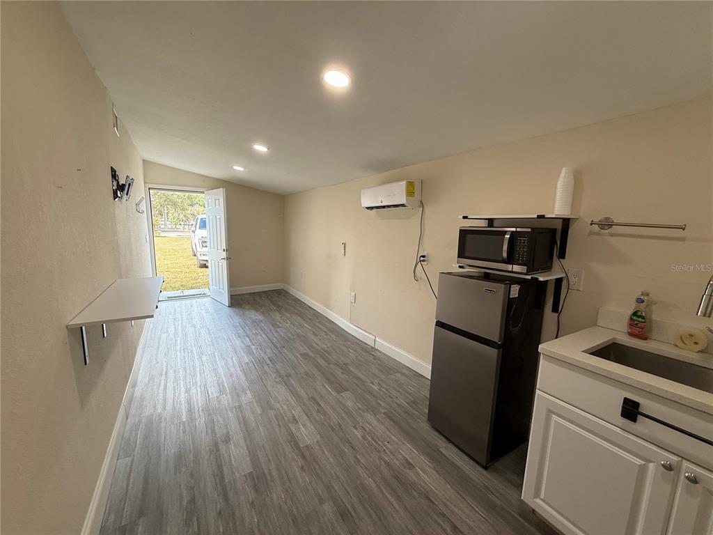 A small kitchen area features a refrigerator, microwave, sink, and wood-look flooring — 5620 1ST STREET UNIT rear, ZEPHYRHILLS, FL