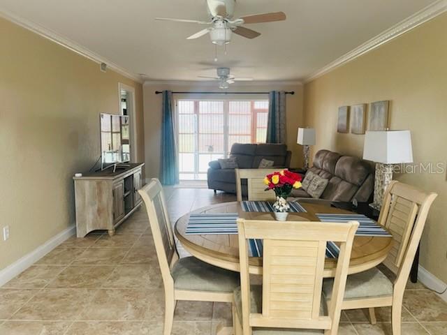 A dining area with a wooden table and chairs opens into a living room space — 1211 SAXONY CIRCLE UNIT A-1, PUNTA GORDA, FL