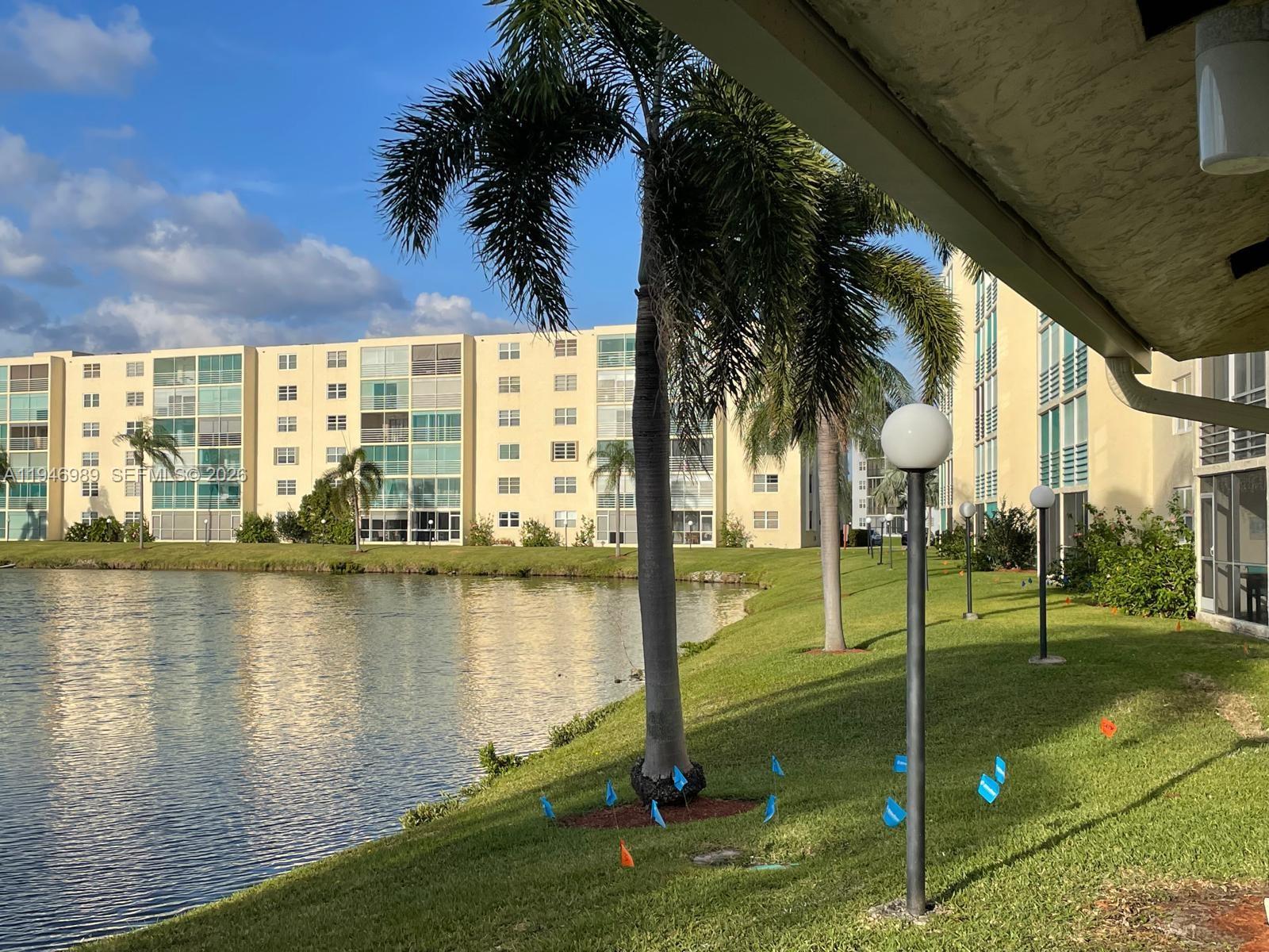 A multi-story apartment building overlooks a lake with palm trees and lawn lighting — 121 SE 3rd Ave # 201, Dania Beach FL 33004, DANIA BEACH, FL