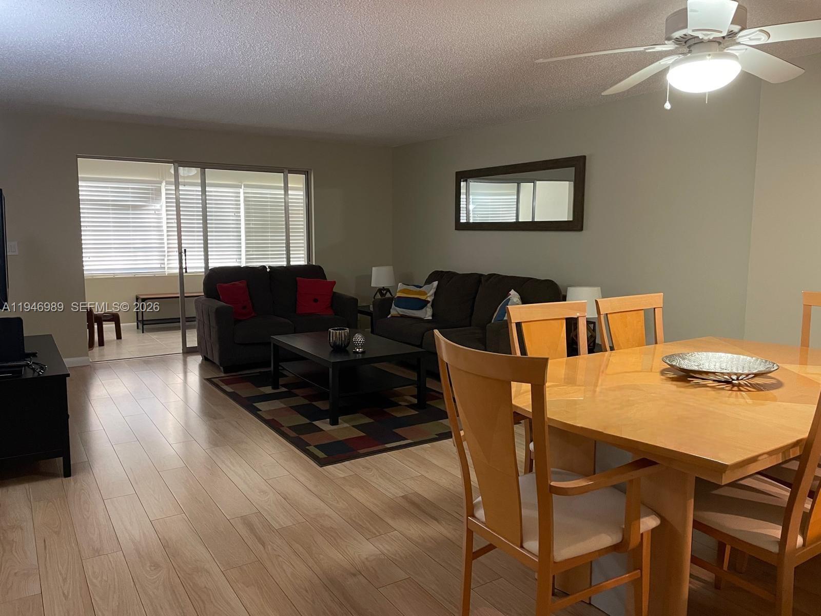 A living and dining area features light wood flooring, a ceiling fan, and sliding doors — 121 SE 3rd Ave # 201, Dania Beach FL 33004, DANIA BEACH, FL