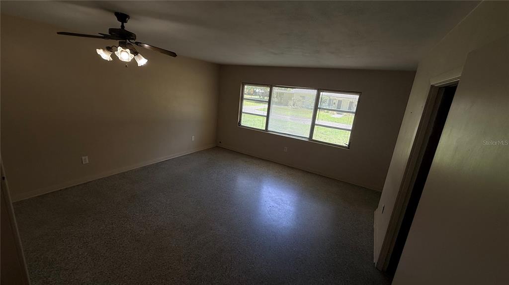 An empty room with beige walls, a ceiling fan, and large windows with blinds — 932 NE 6TH AVENUE, GAINESVILLE, FL