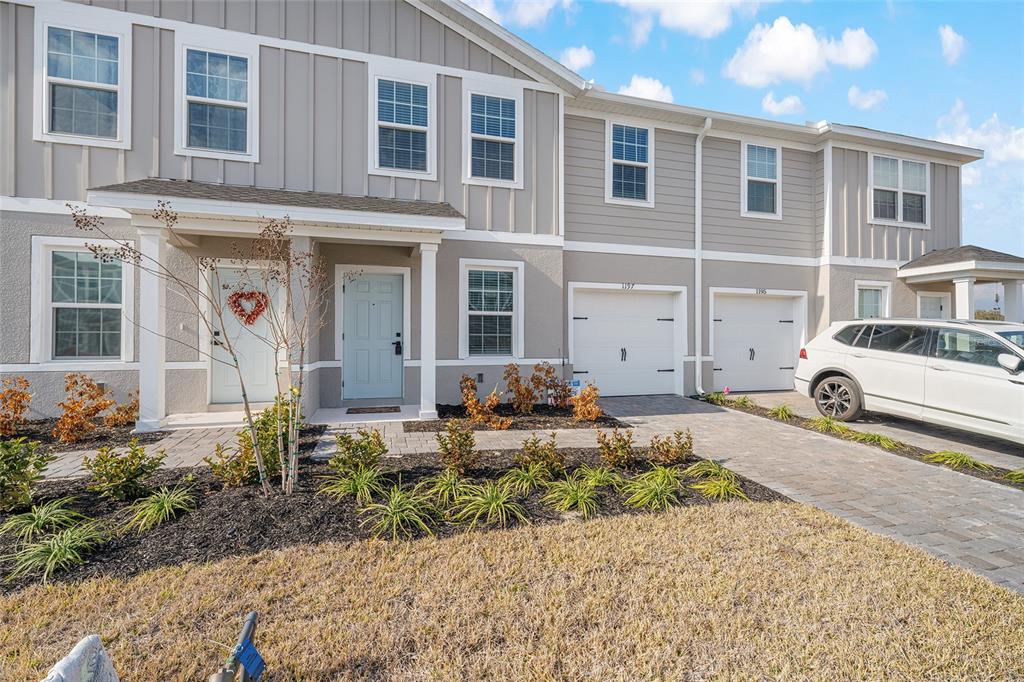 A two-story townhouse exterior features light gray siding, two front doors, and two garage bays — 1197 PORT BLUE WAY, LADY LAKE, FL