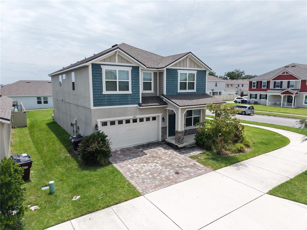 An aerial view of a two-story suburban house with a paved driveway and blue siding — 2436 BLOWING BREEZE AVENUE, KISSIMMEE, FL